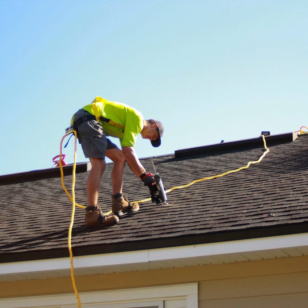 Roofing contractor installing shingles on a residential roof for roofing services near me