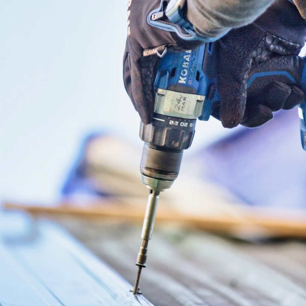 Roofing contractor using a power drill during metal roof installation in Mont Belvieu, TX